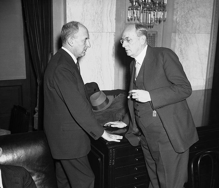 Henry Morgenthau speaks with Attorney General Homer Cummings, who had gone before the Senate Banking Committee to assure members of the constitutionality of FDR's proposal that the Treasury be given title to the Federal Reserve System's gold stocks.
