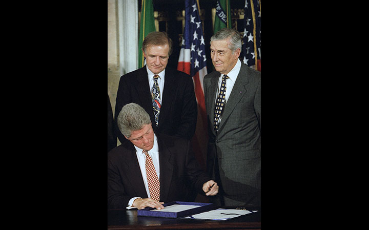President Clinton signs the Interstate Banking and Branching Efficiency Act of 1994 as Senate Banking Committee Chairman Don Riegle and Treasury Secretary Lloyd Bentson look on.