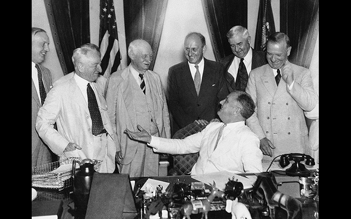 President Roosevelt chats with various politicians and administration officials as he signs the Banking Act of 1935.