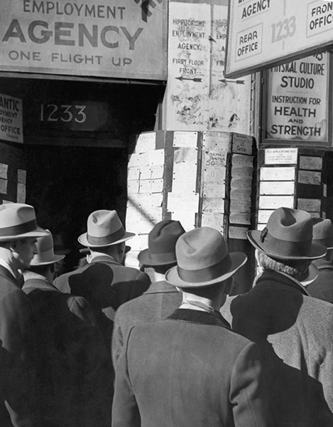 Men study the announcement of jobs at an employment agency during the Great Depression.