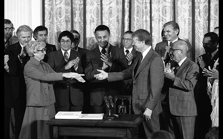 Senator Muriel Humphrey shakes hands with President Jimmy Carter after the signing of the Humphrey-Hawkins Act