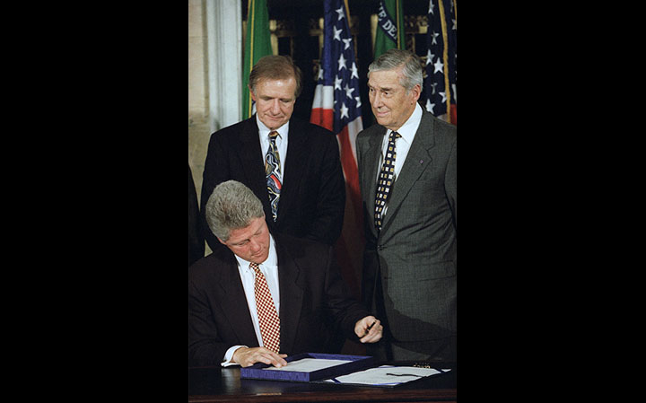 President Clinton signs the Interstate Banking and Branching Efficiency Act of 1994 as Senate Banking Committee Chairman Don Riegle and Treasury Secretary Lloyd Bentson look on.
